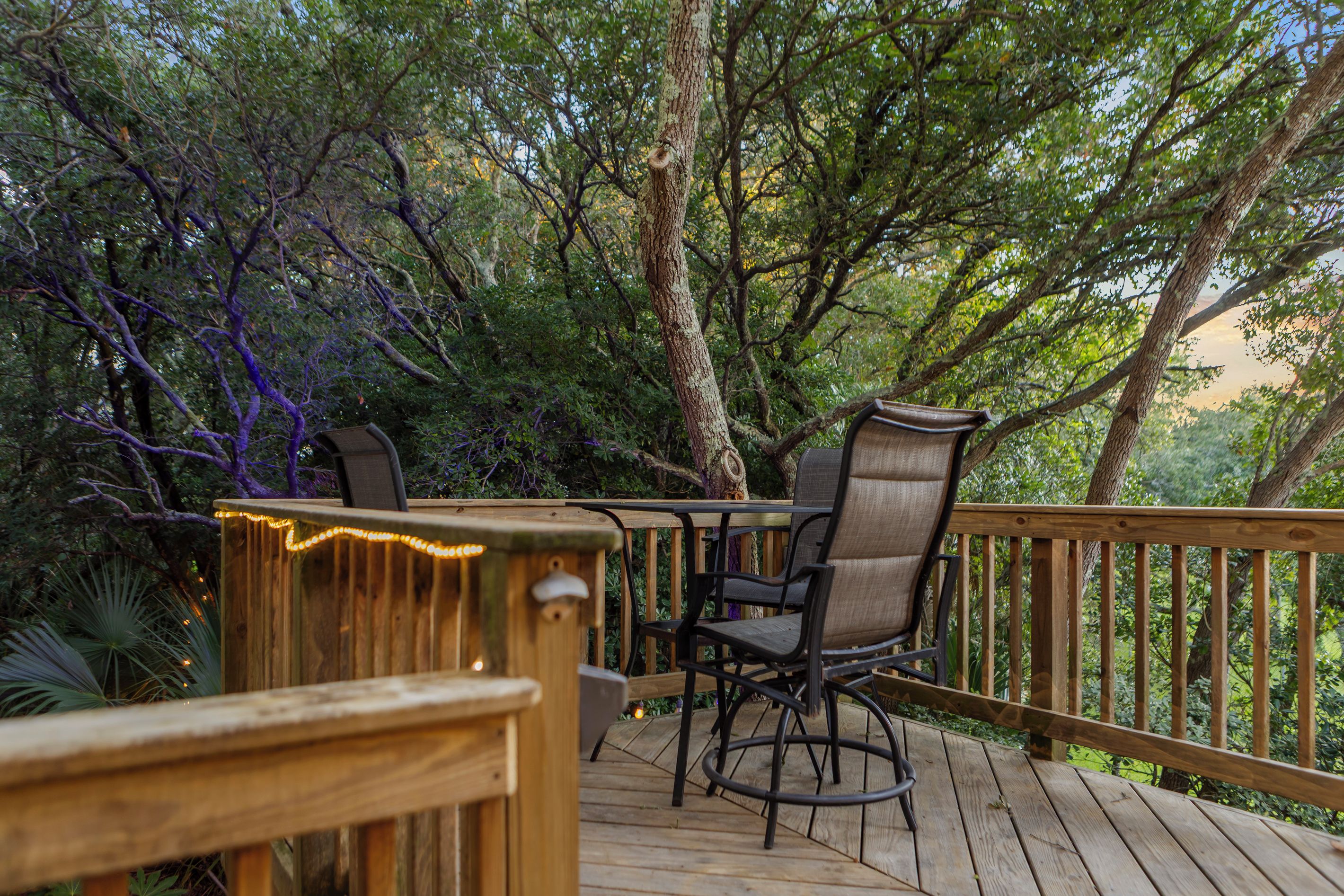 A wooden deck with a table and chairs, surrounded by trees.