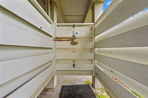 Um corredor estreito com uma grade de metal na base, ladeado por paredes brancas com linhas horizontais.