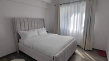 Una camera da letto moderna con un letto, un tappeto morbido e una finestra con tende.