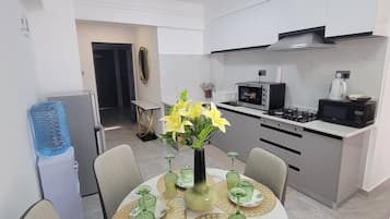 Une cuisine moderne avec des meubles blancs, une cuisinière à gaz et un four à micro-ondes.