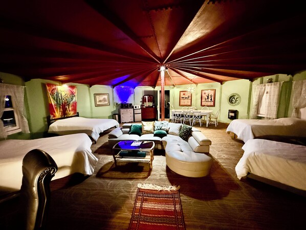 A cozy room with two beds, a sofa, and a dining table.