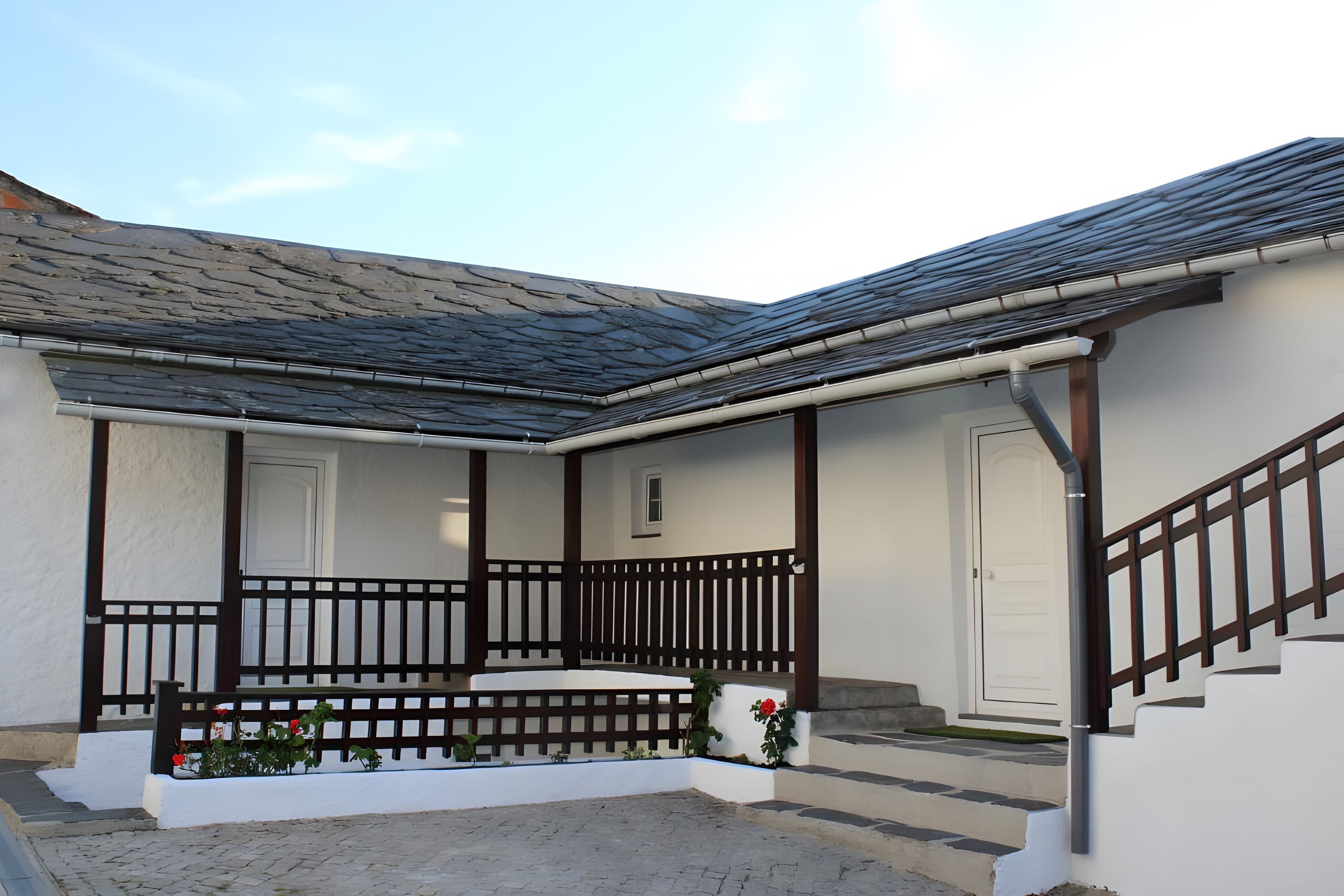 A building with a sloped roof, white exterior walls, and a wooden staircase leading to a porch.