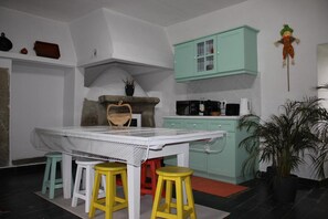 Una cocina con una mesa blanca, taburetes amarillos, un armario verde y una planta en maceta.
