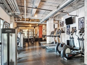 A gym with treadmills, elliptical machines, and weightlifting equipment. - The Bentley Collection - The Vinyl Loft (Dallas)