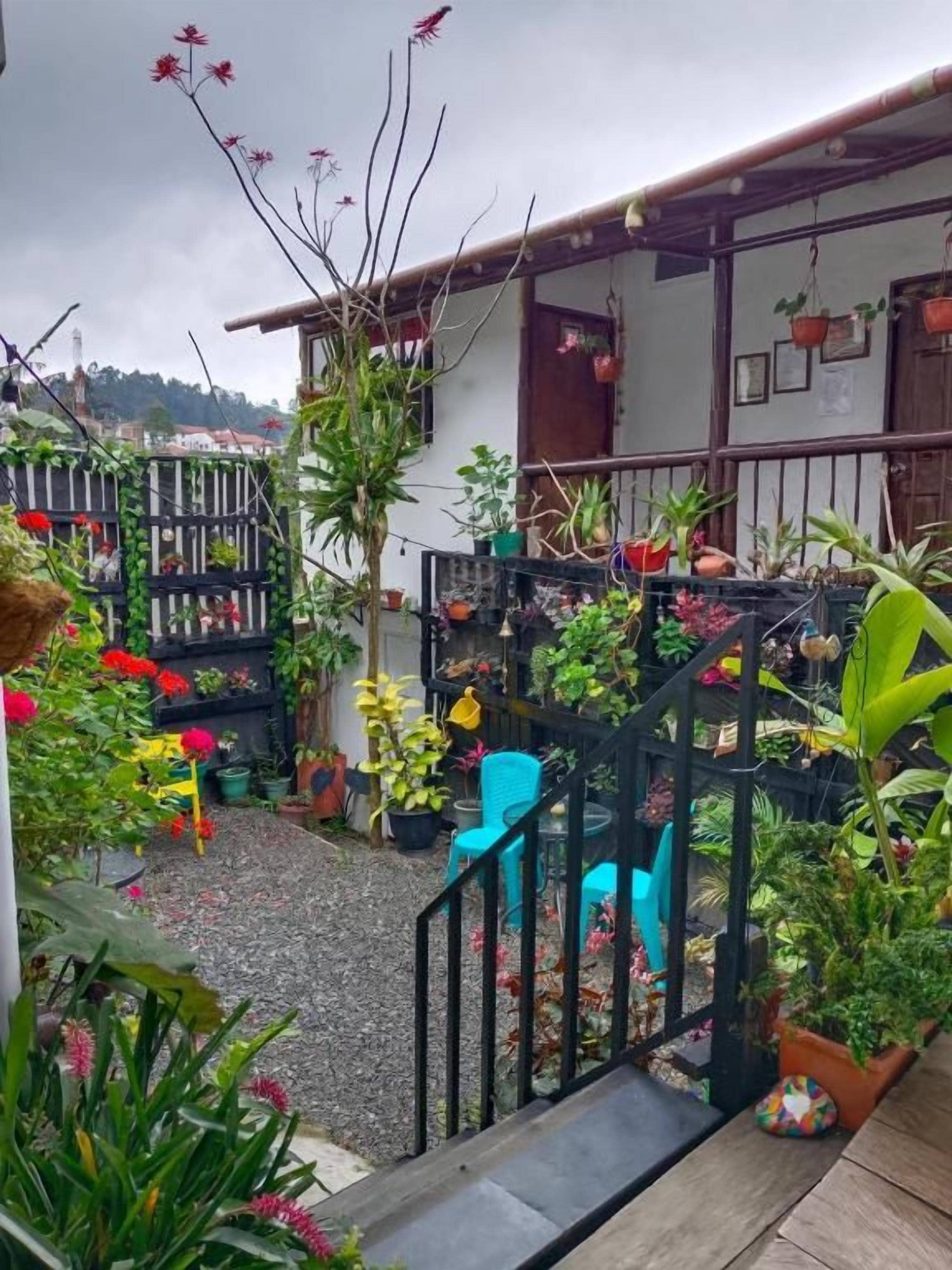 A courtyard with potted plants, a staircase, and a building with a balcony.