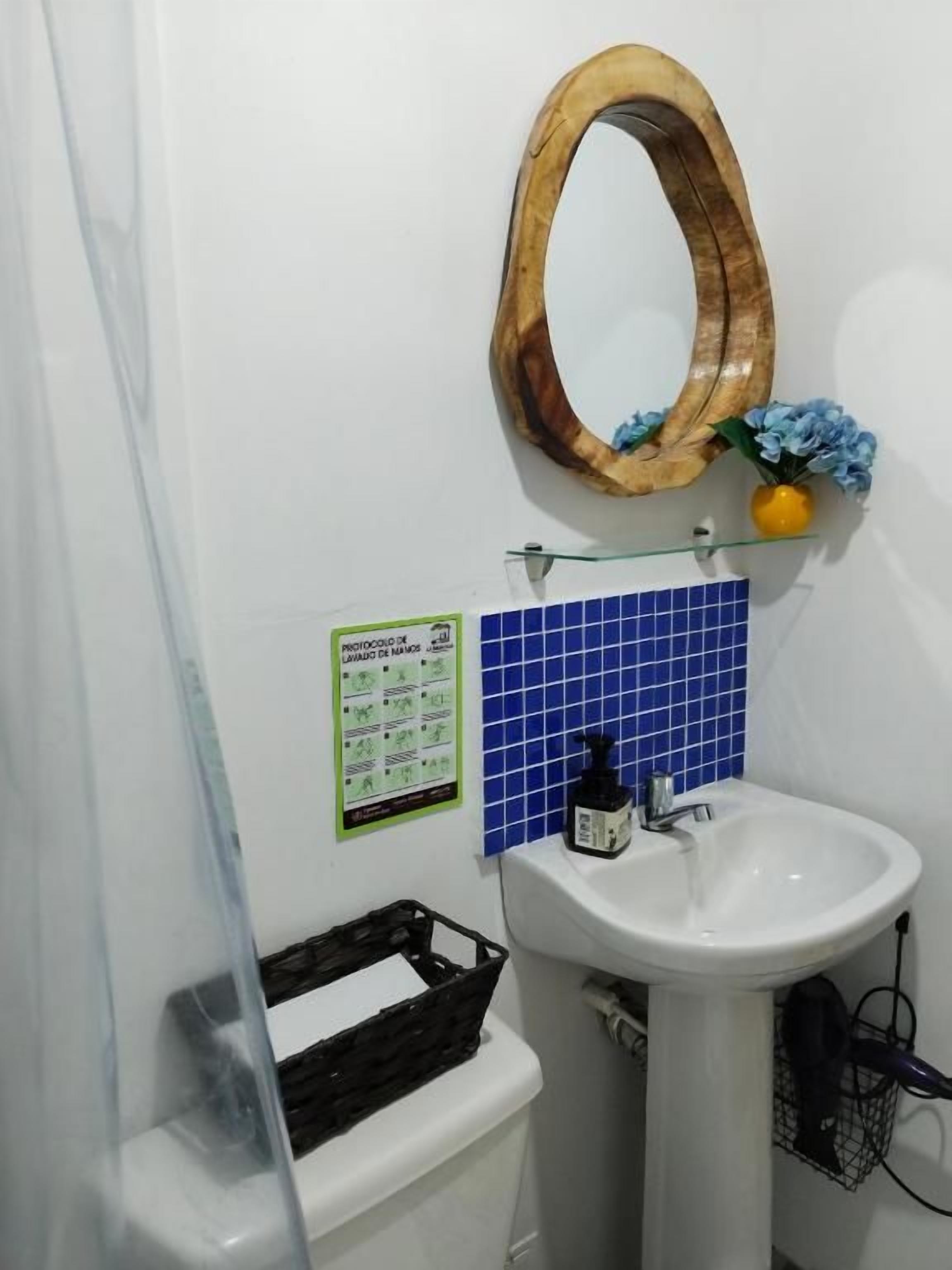 A bathroom with a white sink, a wooden-framed mirror, and a blue tiled backsplash.