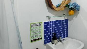 A bathroom with a white sink, a wooden-framed mirror, and a blue tiled backsplash.