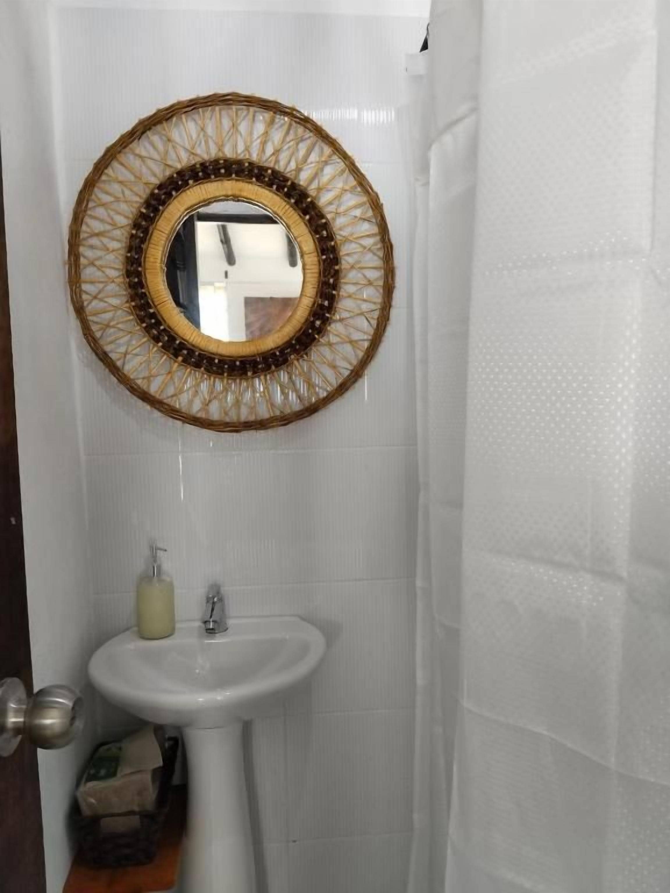 Un baño con un lavamanos blanco, un espejo con marco decorativo y una cortina de ducha.