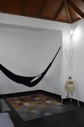 A room with a hammock, a standing lamp, and a patterned rug.