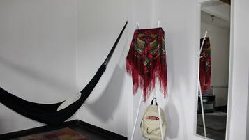 A hammock, a decorative hanging piece, and a bag with a label in a room with a tiled floor and a mirror.