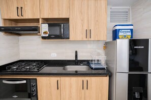 Eine Küche mit Holzschränken, einer Mikrowelle, einem Gasherd, einem Geschirrspüler und einem Kühlschrank.