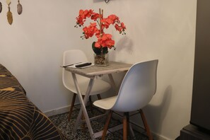 A small dining area with a table, chairs, and a vase with red flowers. - Segovia Room—Near the Airport (Carolina)