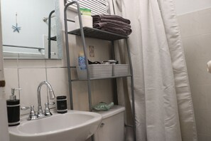 A bathroom with a sink, a mirror, a towel rack, and a shower curtain. - Segovia Room—Near the Airport (Carolina)