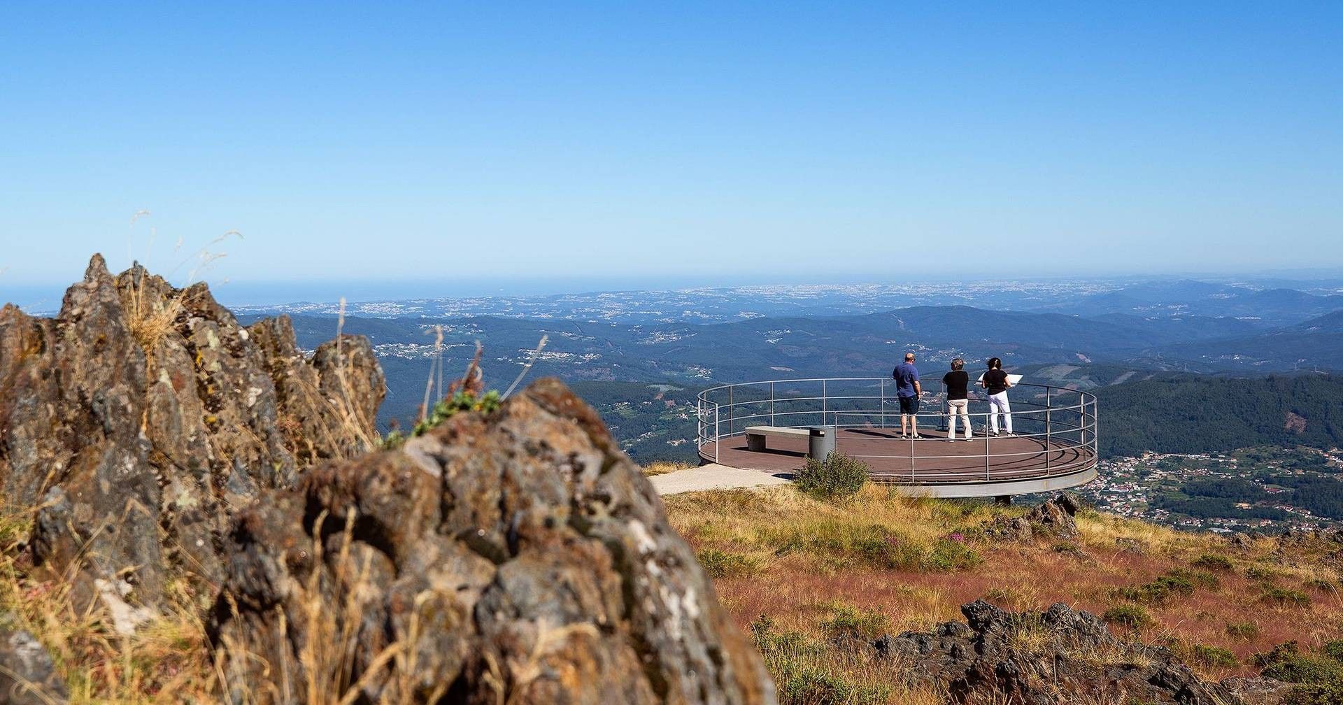 A rocky overlook with a circular viewing platform and a panoramic view of a valley.