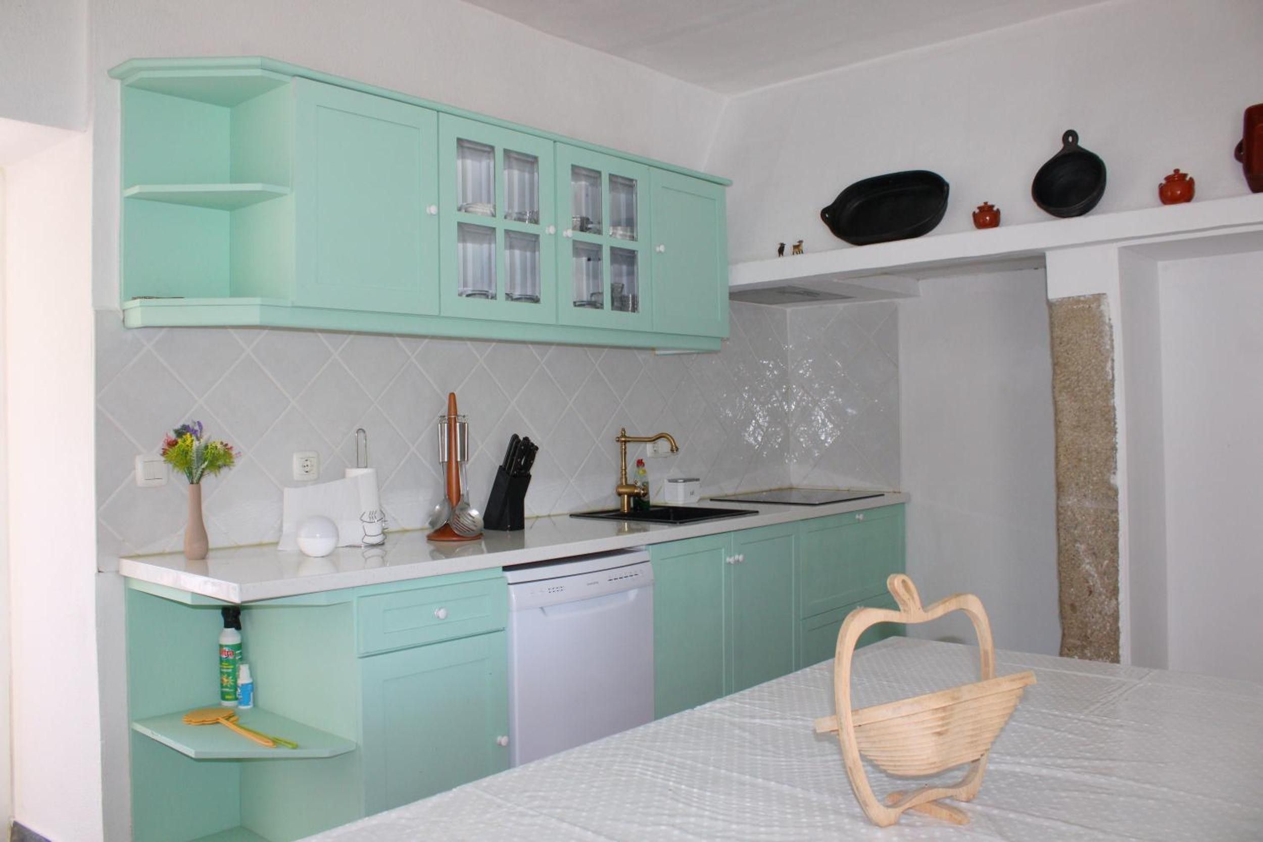 A kitchen with teal cabinets, a white countertop, and a wooden chair.