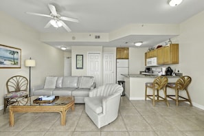 A living room with a sofa, a coffee table, and a dining area with chairs. - Boca Ciega Bay Resort – Top Floor Bay Views #414 (St. Petersburg)