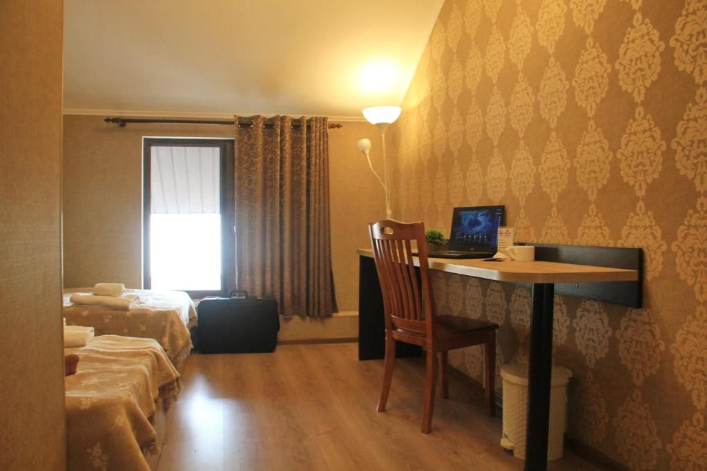Habitación de hotel con escritorio, silla, computadora y dos camas.
