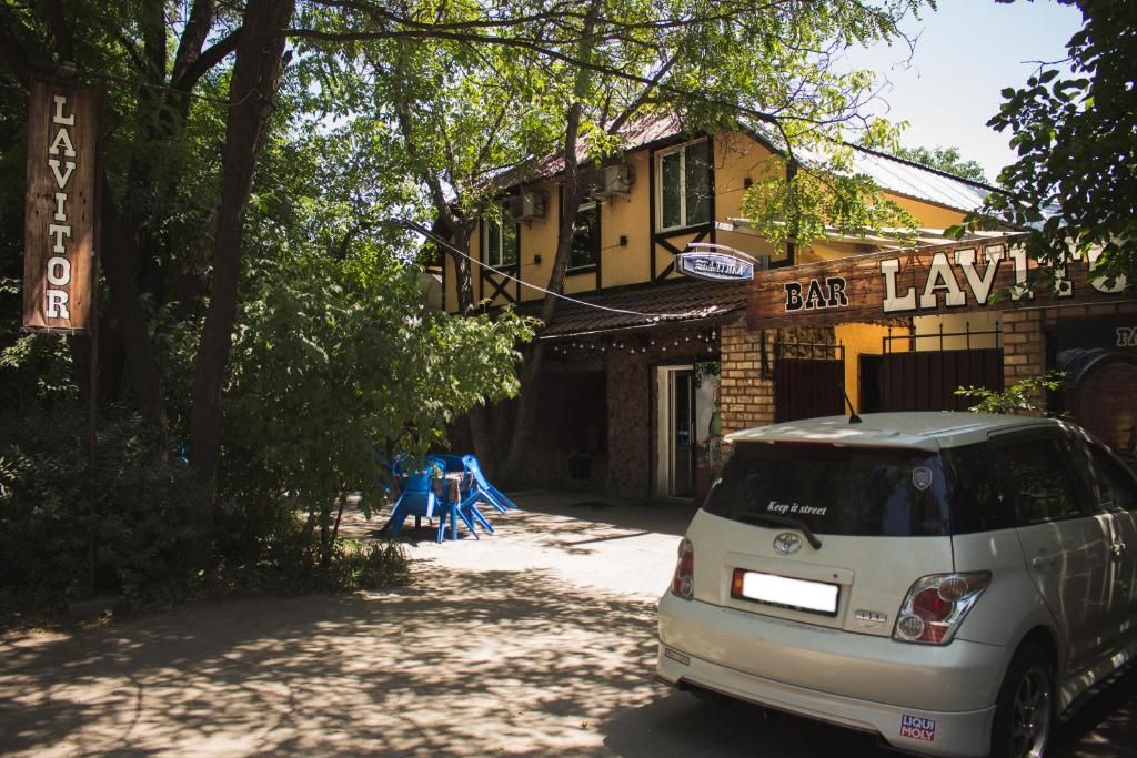 Un edificio con un letrero que dice 'BAR LAVITORS' y un coche estacionado en la calle.