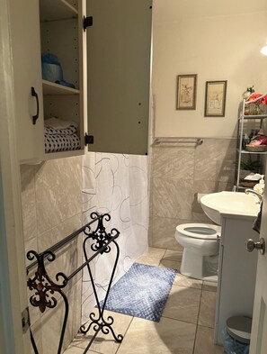 Et badeværelse med toilet, håndvask og bruseområde.