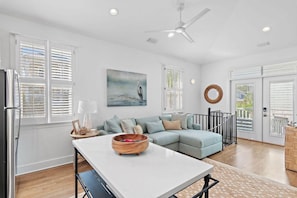 A modern living room with a light blue sofa, a white coffee table, and a painting of a bird on the wall. - Palms by the Sea (Panama City Beach)