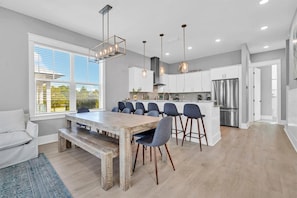 Een moderne keuken met een centraal eiland, barkrukken en een eettafel.