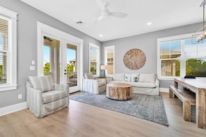 A spacious living room with a sofa, armchairs, a coffee table, and a dining area with a bench. - Palms by the Sea (Panama City Beach)