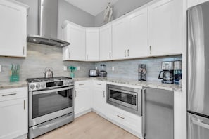 A modern kitchen with white cabinetry, stainless steel appliances, and a marble countertop. - Palms by the Sea (Panama City Beach)
