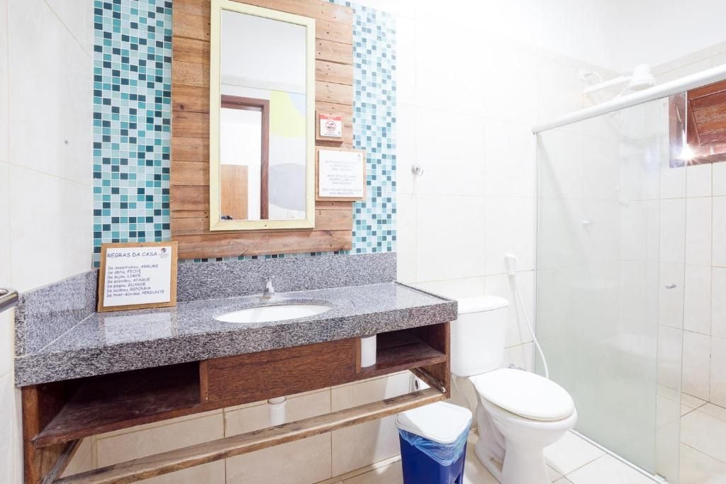 Un baño con encimera de granito, tocador de madera, lavabo blanco, espejo y cabina de ducha de vidrio.