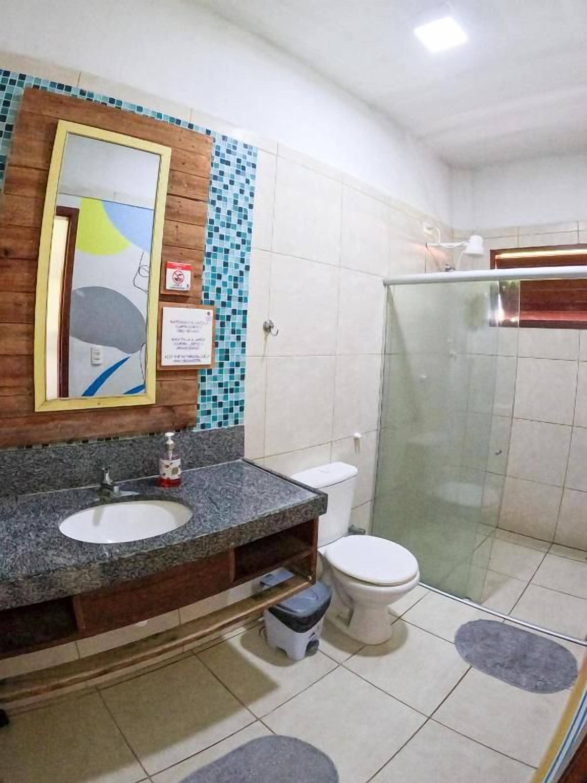 A bathroom with a granite sink, a toilet, and a glass shower enclosure.
