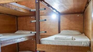 Quarto com beliche de madeira, barra de exercícios e um pequeno espaço para guardar pertences.