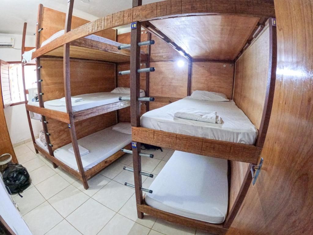 A bunk bed room with wooden frames and white bedding.