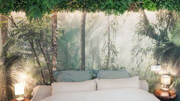 Ein Bett mit weißer Matratze, zwei Kissen und einem Kopfteil mit einem Wald-Mural. Es gibt zwei Nachttische mit Lampen.