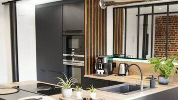 A modern kitchen with a built-in oven, a coffee machine, and a sink.