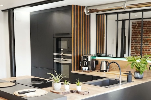 A modern kitchen with a built-in oven, a coffee machine, and a sink. - L'Oasis - Hydrotherapy Spa, Movie Theater & Relaxation by the Sea (AULT)