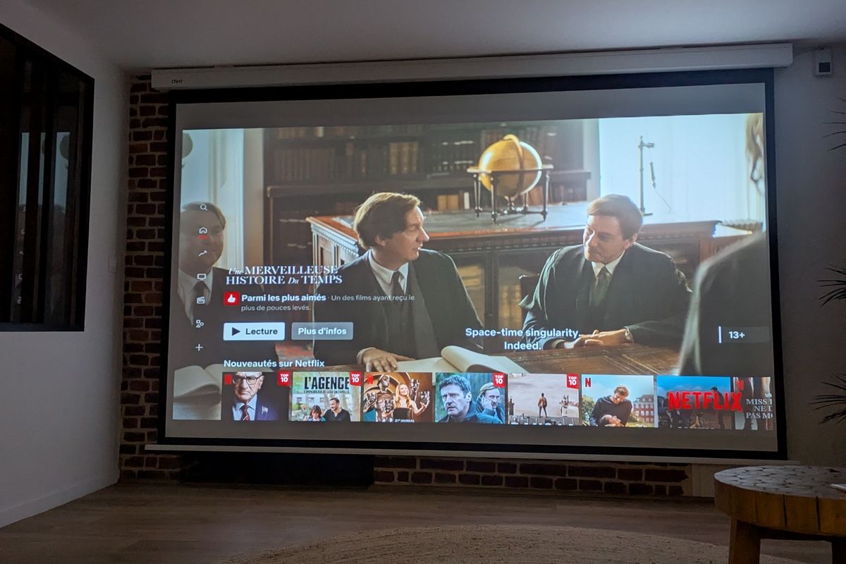 A television screen displaying a movie scene with a bookshelf in the background.