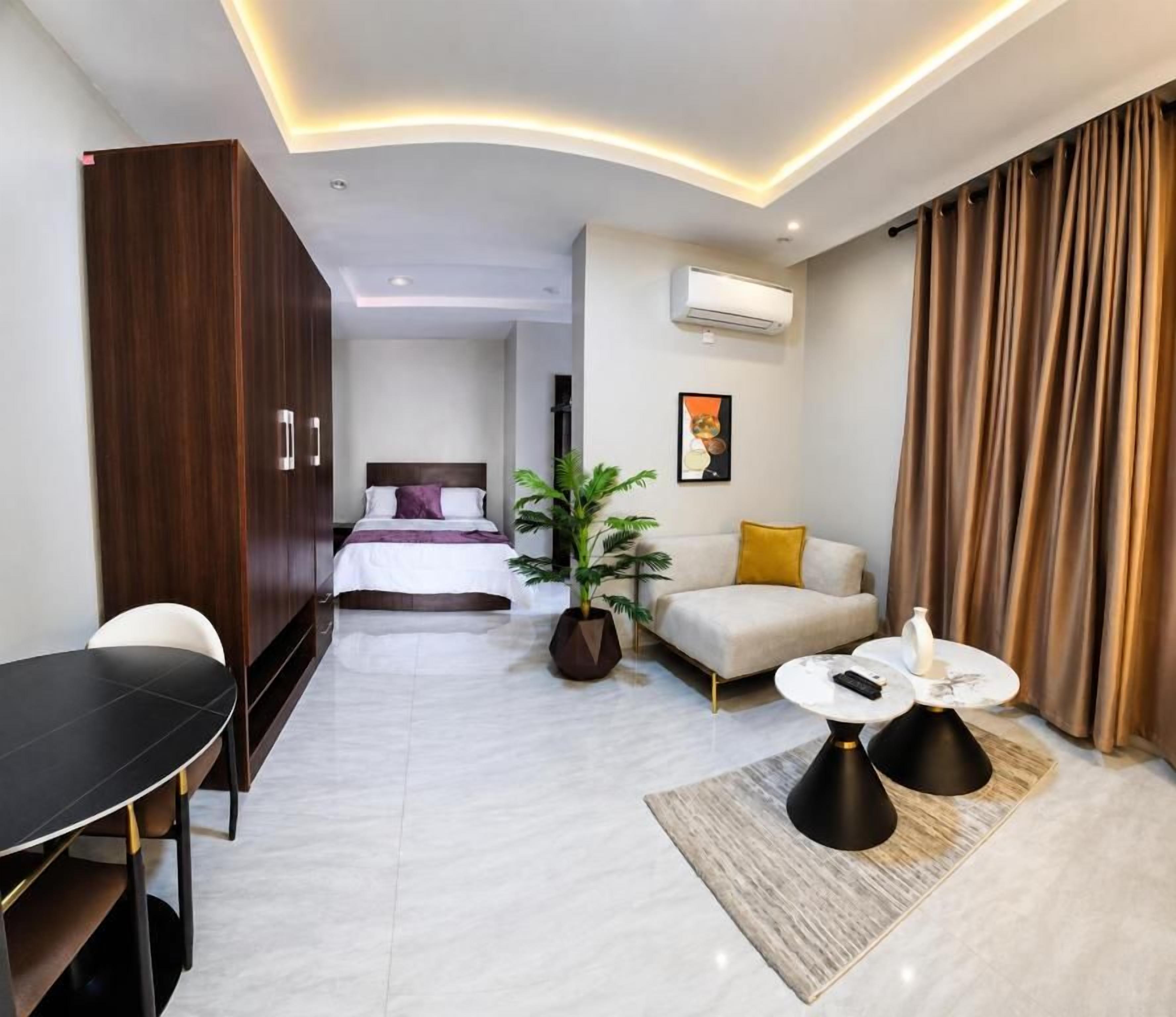 Una habitación de hotel moderna con una cama, un sofá, una mesa de comedor y una mesita de centro.