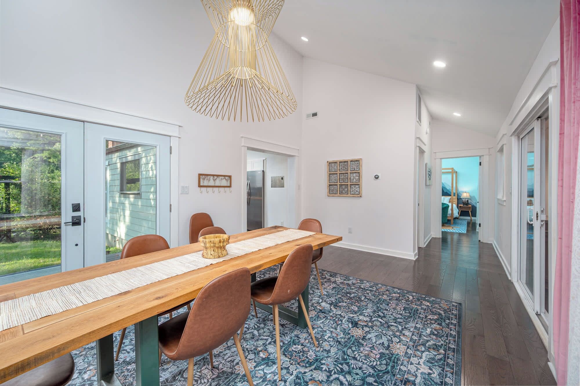 A modern dining area with a wooden table, brown chairs, and a patterned rug.