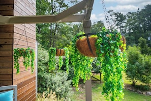 Paret exterior de fusta amb planters penjants plens de vegetació verda.