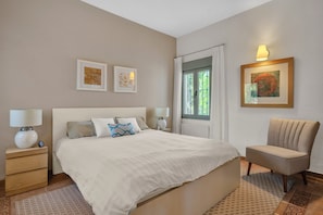 Ein Schlafzimmer mit einem Bett, Nachttischen, einem Sessel und Bildern an den Wänden.