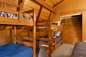 A wooden cabin with bunk beds, a small table, and a door leading to a closet. - Moose Moritz Manor #2667 (Big Bear Lake)