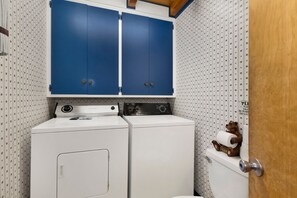 A laundry room with two washing machines, a dryer, and a wooden bear decoration on the toilet. - Moose Moritz Manor #2667 (Big Bear Lake)