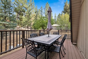 A patio with a table and chairs, an umbrella, and a view of trees. - Moose Moritz Manor #2667 (Big Bear Lake)