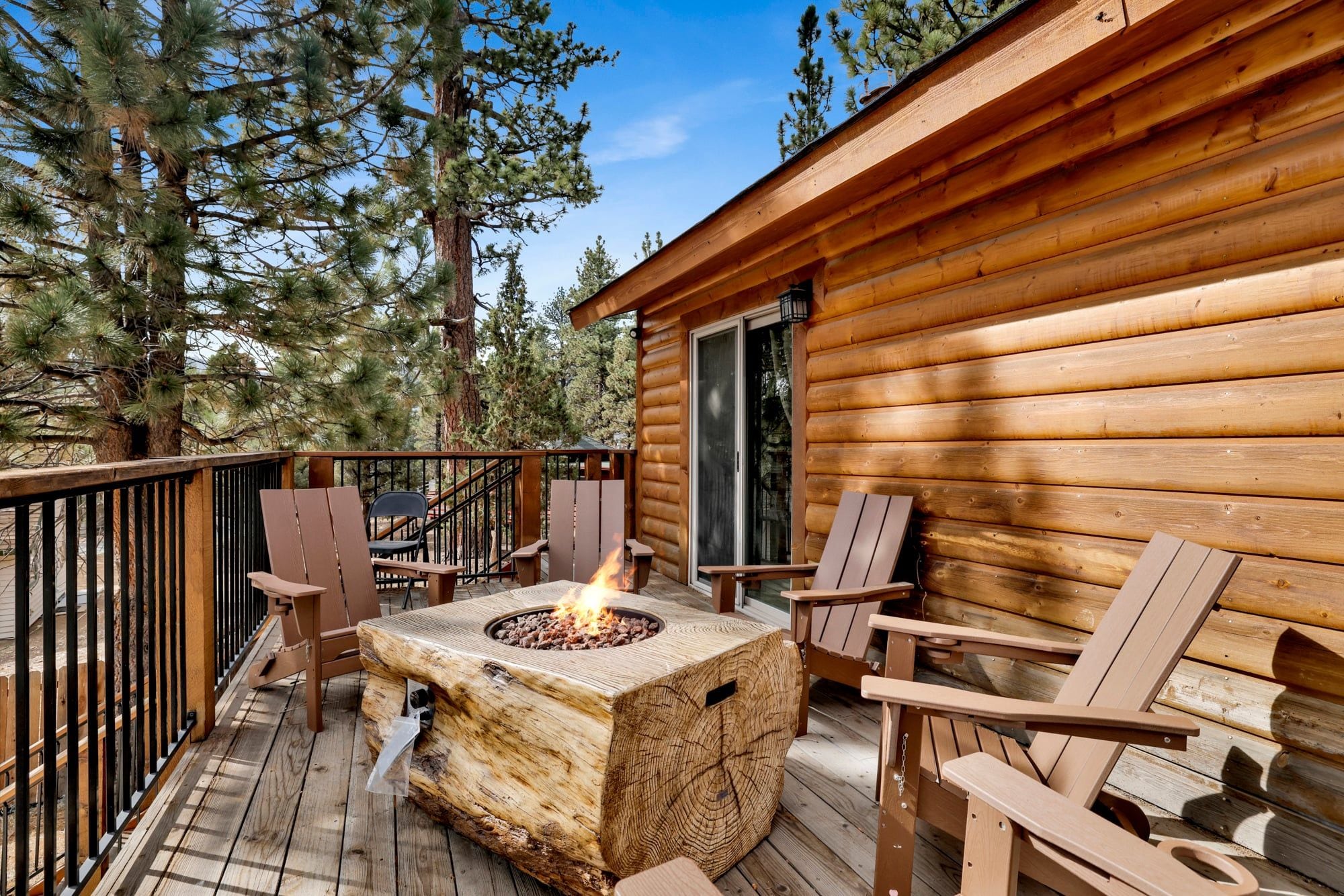 A wooden cabin with a deck, outdoor seating, and a fire pit.