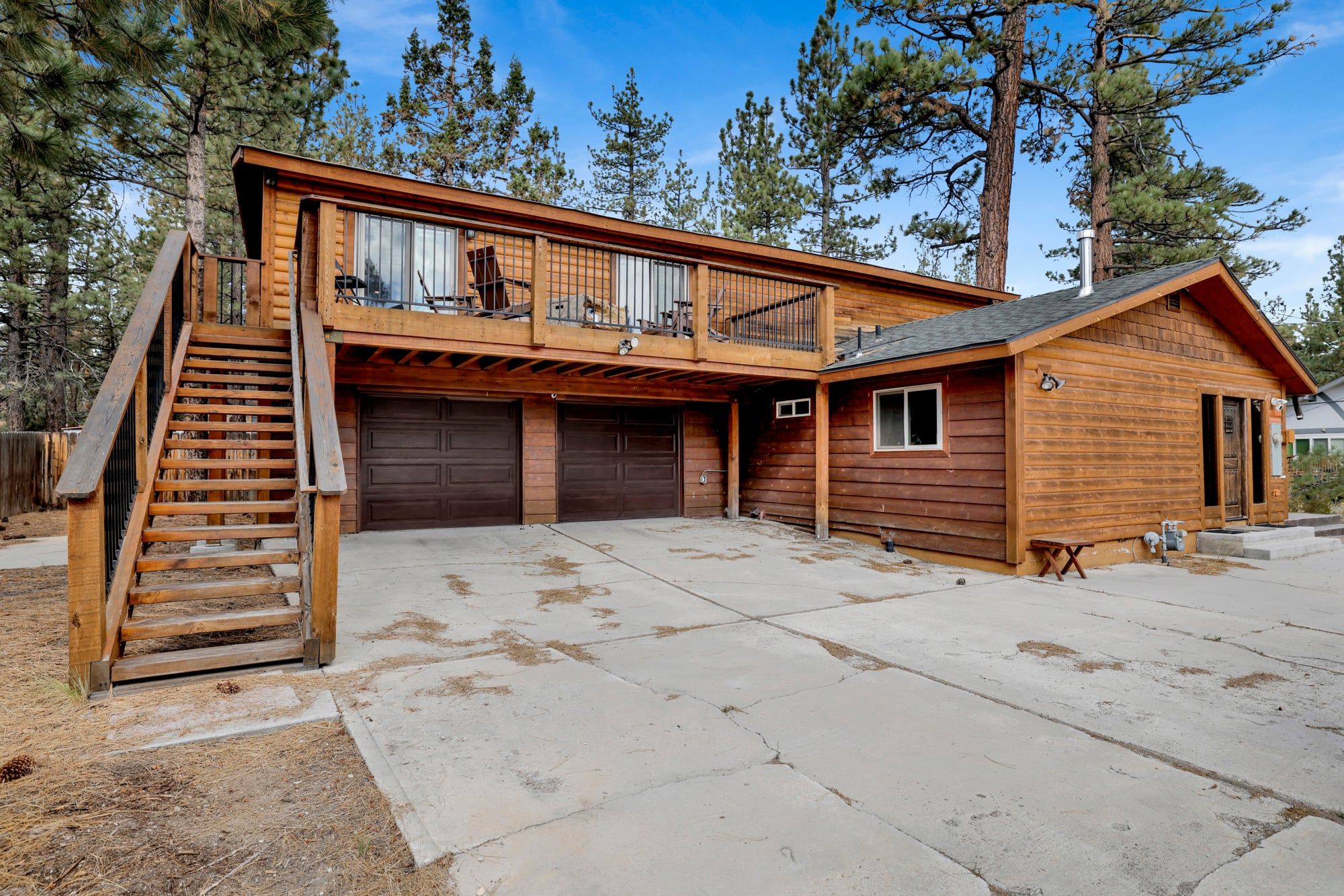 A two-story wooden cabin with a balcony, a covered porch, and a garage.
