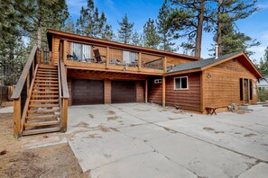 A two-story wooden cabin with a balcony, a covered porch, and a garage. - Newsom's Hideaway (Big Bear City)