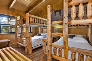 Een rustieke houten chalet met stapelbedden, een houten bank en een raam met uitzicht op een balkon.