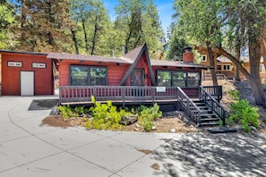 Eine rote Holzhütte mit einem Balkon, einer Treppe und einem kleinen Garten.