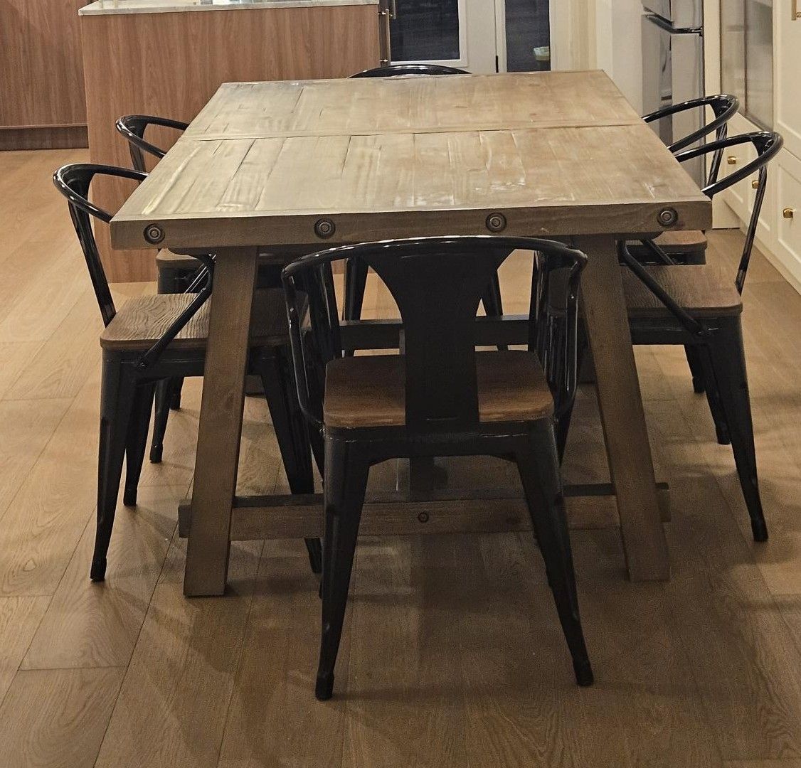 A rectangular wooden dining table with six chairs, each with a curved backrest.