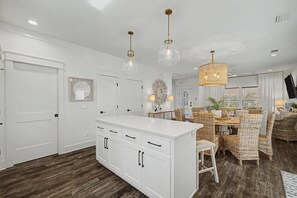 A modern kitchen with white cabinetry, a central island, and pendant lighting. - Stay Sunny | Bikes, 1-2 min Beachwalk, NEW (Panama City Beach)