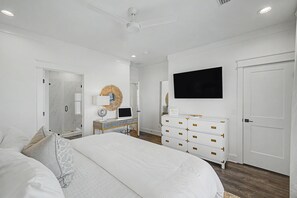 Ein Schlafzimmer mit einem Bett, einem Schminktisch, einem Fernseher und einem Deckenventilator.